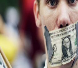 A demonstrator from the Occupy Wall Street campaign stands with a dollar taped over his mouth in Zucotti Park near the financial district of New York